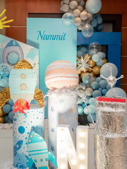 A detailed decor corner with custom-made rocket ships, planet models, and illuminated letters for the birthday boy's name.