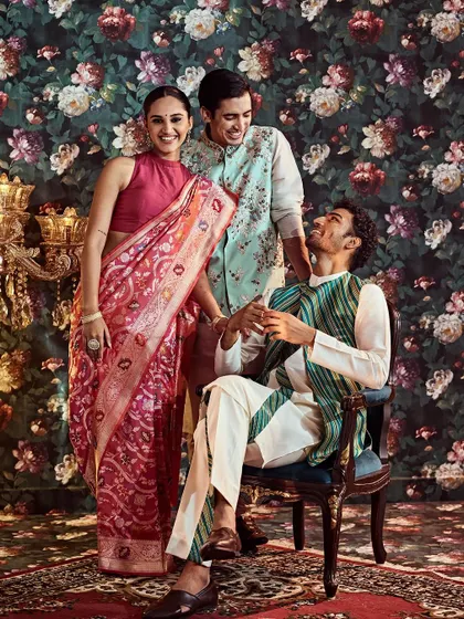 The warmth of family and festivities. This group showcases a cohesive look for a wedding event, with a red Banarasi saree complemented by pastel blue and striped green jackets for the men.