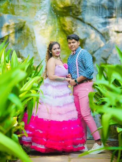This fun and colorful pre-wedding photo showcases a playful couple's style. The tiered pink and white gown coordinates perfectly with the partner's pink trousers and suspenders.