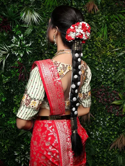 A detailed shot of the bride's traditional South Indian hairstyle. The intricate braid, adorned with flowers and pearls, and the beautiful blouse design are the focus of this elegant portrait.