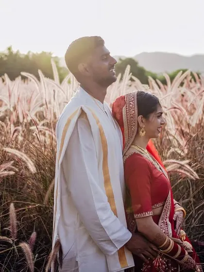 A beautiful portrait of the couple standing back-to-back in a field, bathed in the golden light of the setting sun.