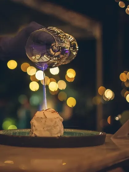 A dramatic dessert presentation with a flaming liqueur being poured over it.