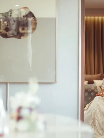 A bride in a simple white outfit, captured in a quiet moment of reflection before the wedding festivities begin.