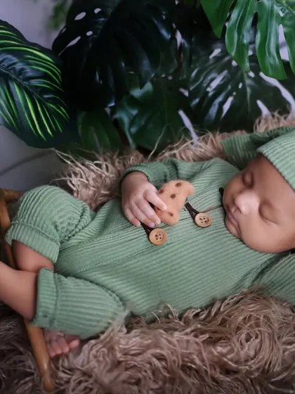 Surrounded by lush green leaves, this newborn sleeps peacefully. This setup creates a beautiful, nature-inspired portrait right in the comfort of our studio.