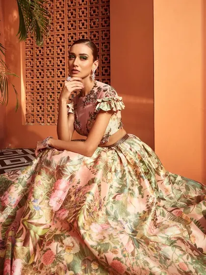 A floral printed lehenga paired with a modern ruffled blouse. This look is perfect for a spring or summer wedding, offering a fresh and romantic alternative for a Mehendi or day event.