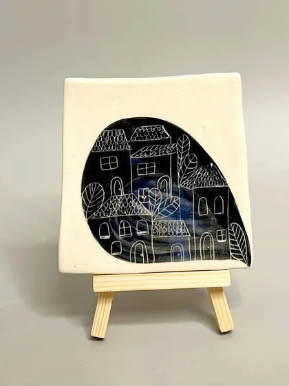 A square ceramic tile with a charming, hand-carved illustration of a village. These tiles add a touch of elegance and charm to any room in your home.