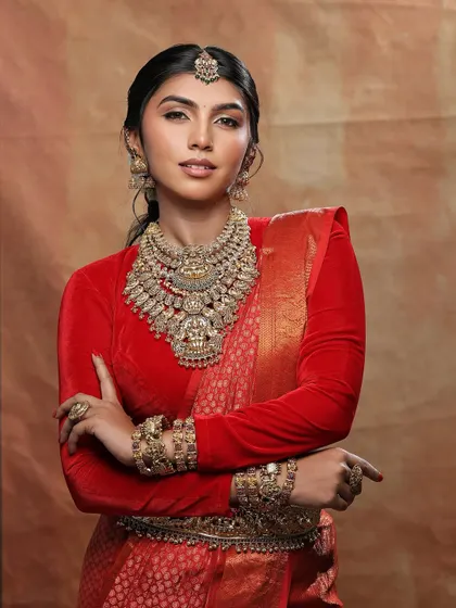 A regal reception look in a classic red saree. The makeup is soft and glamorous, with a focus on glowing skin and defined eyes.
