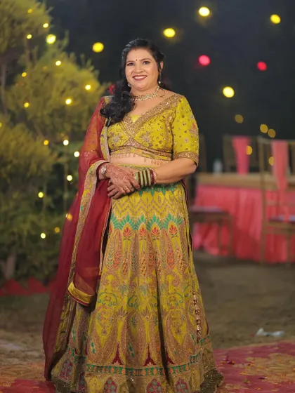 A happy client looking radiant in a multi-color threadwork lehenga. The vibrant colors and intricate design make it a perfect outfit for a mehndi or sangeet ceremony.