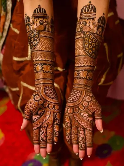 This design features majestic palace domes and peacocks, set against a rich red background. The dark henna paste creates a striking contrast.