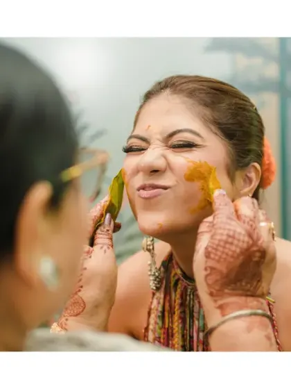 A playful moment as the bride makes a funny face while getting haldi applied. It's these lighthearted, real moments that truly tell the story of the day.