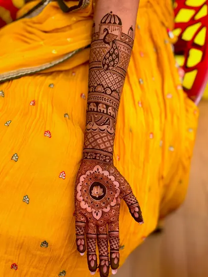 A close-up of the arm, featuring a peacock motif and an elephant procession, classic elements of bridal henna.