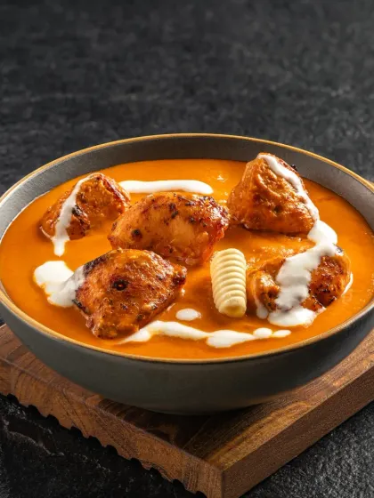 Chicken Tikka Masala, with perfectly cooked chicken in a creamy tomato-based sauce. The image is styled to look hearty and inviting.