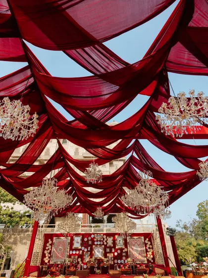 An upward view of the magnificent red fabric ceiling and crystal chandeliers. This element of the 'Laal Ishq' decor added a sense of grandeur and opulence to the entire wedding venue.