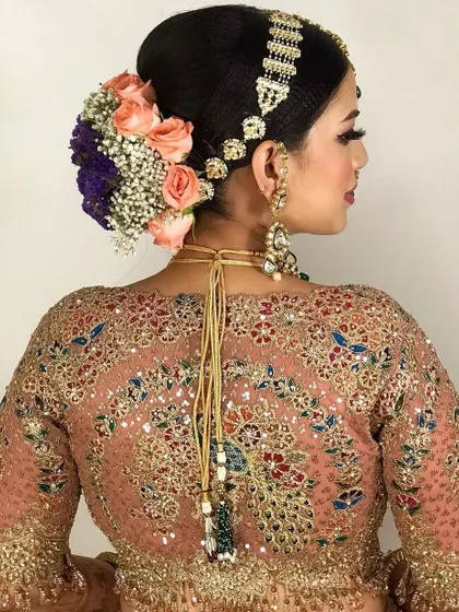 A gorgeous bridal updo with a mix of roses and baby's breath. The hairstyle is designed to look beautiful from every angle.