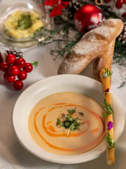 A warm bowl of creamy mushroom soup served with a decorated breadstick, a comforting starter from our multi-course Holiday Feast.