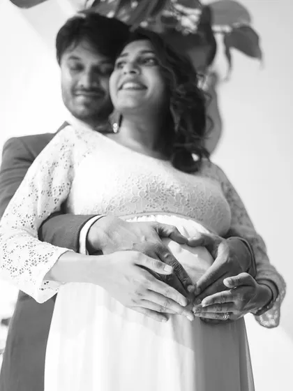 A beautiful, intimate black and white moment. The couple's hands forming a heart on the baby bump is a classic symbol of their shared love and excitement.