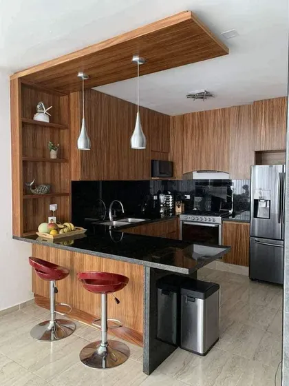 This kitchen features a beautiful wooden breakfast bar with red stools that add a fun pop of color. The black granite countertops provide a durable and stylish work surface.