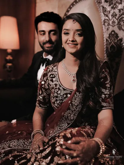 A classic reception portrait of the couple, with the bride smiling at the camera and the groom looking on admiringly.