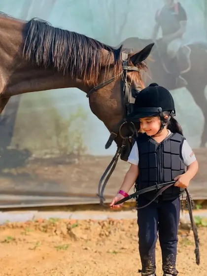 A child gently leads her horse, showing the trust and respect we nurture between our riders and animals.