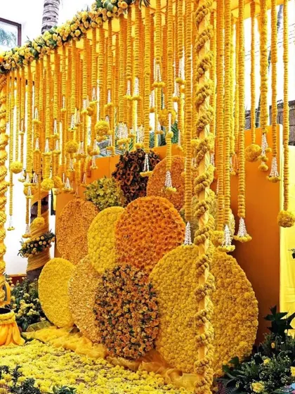 A stunning and creative Haldi backdrop made from circles of marigolds in different shades of yellow and orange. This design offers a modern twist on traditional Haldi decor.