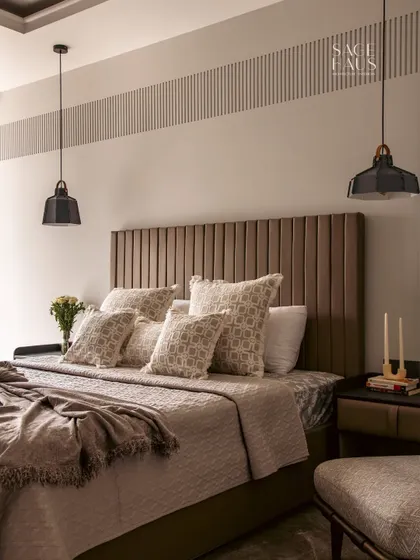 A wide shot of this calming bedroom retreat, showing the symmetry of the pendant lights and bedside tables. The layered bedding and plush pillows add to the feeling of comfort and understated luxury.