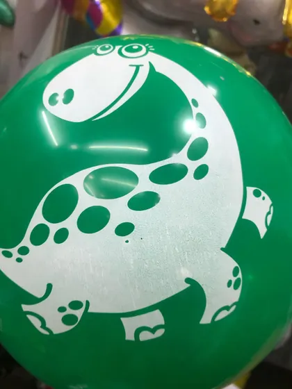 A close-up of our green latex balloon with a friendly dinosaur print, perfect for a jungle or dinosaur-themed party.