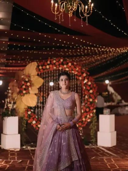 A beautiful solo portrait of the bride against the reception stage. The grand floral arch and twinkling lights create a magical backdrop that makes her shine even brighter.