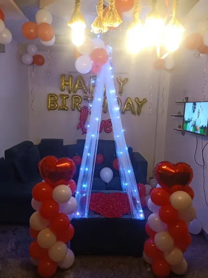 A romantic birthday surprise setup for a loved one. The canopy with fairy lights, heart-shaped balloons, and rose petals creates a very special and intimate atmosphere.