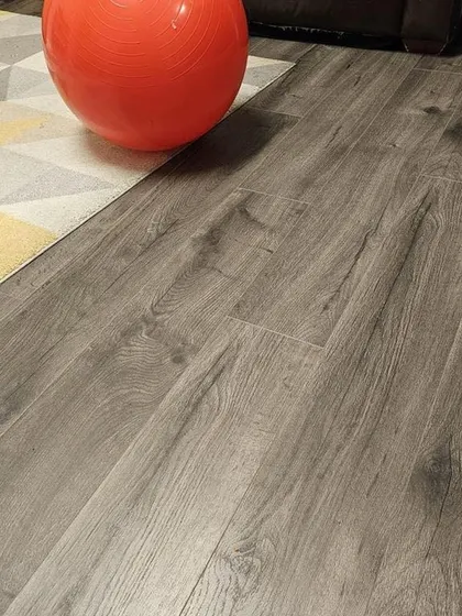This grey wood-look laminate flooring is a popular choice for modern homes. It offers a chic, neutral tone that is incredibly versatile and durable, as seen here in this casual living space.