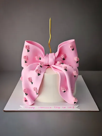 The famous bow cake, this time for Women's Day. This vanilla cake with chocolate truffle is decorated with a large pink bow adorned with tiny roses.