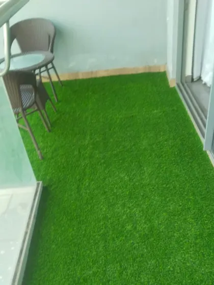 A complete view of the 35mm artificial grass installation. It's neatly finished along the edges for a professional look, transforming a standard balcony into a personal lawn in the sky.