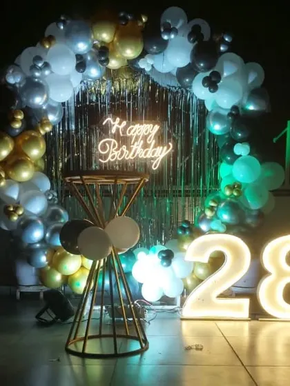 A stylish rooftop decoration for a 28th birthday, with a balloon ring, shimmer curtain, and light-up numbers creating the perfect party spot.