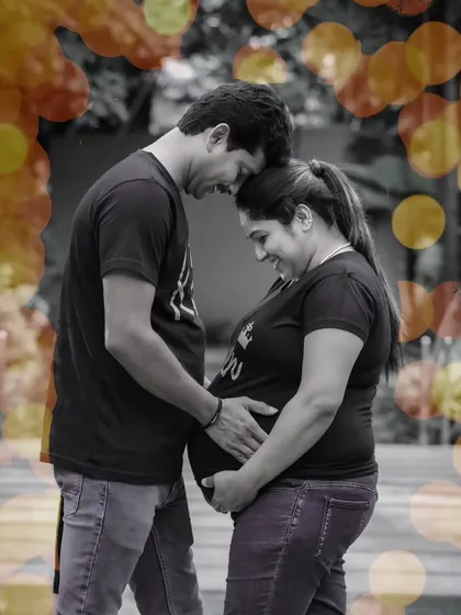 A beautiful black and white portrait of an expecting couple, with a touch of color from the bokeh effect, creating a timeless and artistic image.