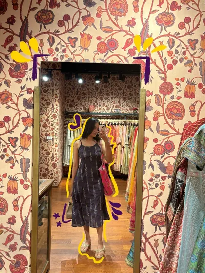 A mirror selfie in a pretty boho dress, with a yellow outline to make it stand out against the patterned wallpaper.