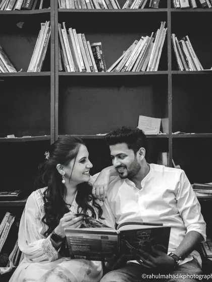 A black and white shot of the couple sharing a book in a library setting. This themed photo is a wonderful way to incorporate a shared hobby into a pre-wedding shoot, making it personal and unique.