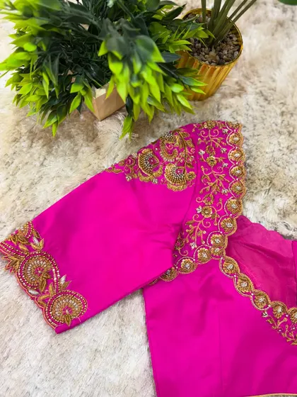 A bright pink blouse with heavy, ornate gold embroidery covering the entire sleeve in traditional patterns.