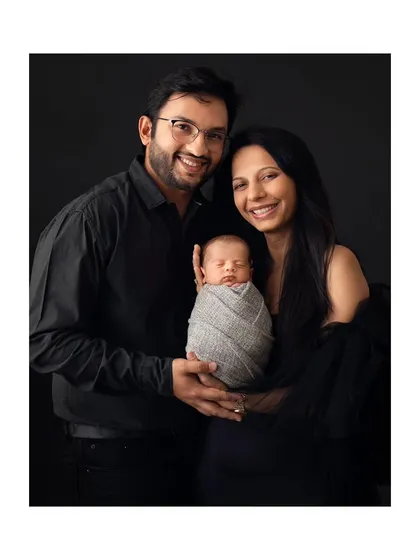 A smiling family portrait against a simple dark background, full of joy and love.