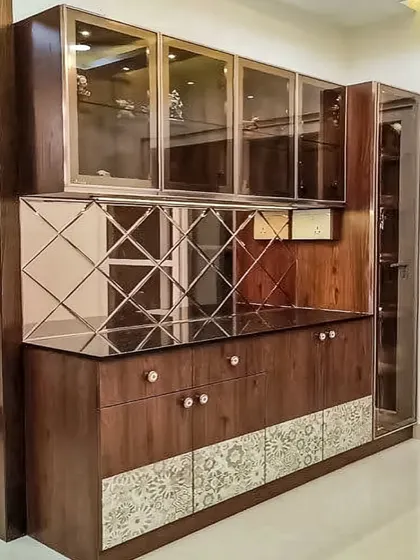 A classic crockery unit in a rich wood finish with elegant details. The design features glass-front upper cabinets, a diamond-patterned mirror backsplash, and patterned lower cabinet doors.