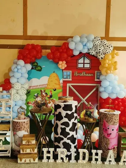 A fun and colorful farmland theme, complete with a red barn backdrop, cow-print pedestals, and cute farm animal cutouts.