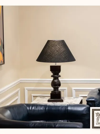 A closer look at the classic black table lamp, highlighting the texture of the lampshade and the detailed carving on its wooden base. It's a versatile piece that complements a modern classic interior.