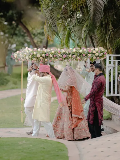 The bride's grand entrance under a stunning phoolon ki chaadar made of fresh pink and white roses.