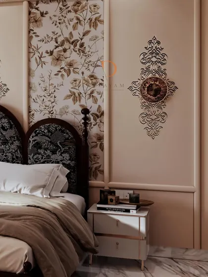 A close-up of a neo-classical bedroom, highlighting the elegant wall mouldings, floral wallpaper inserts, and a beautifully curved upholstered headboard.