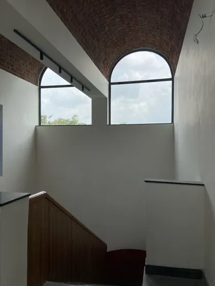 The large arched windows at the end of the brick vault, designed to let in natural light and offer views of the sky and surrounding flora.