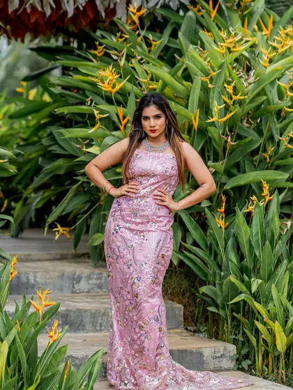 A full-length view of the pink sequined gown against a lush green background. The color and sparkle make it a truly eye-catching piece for any grand occasion.