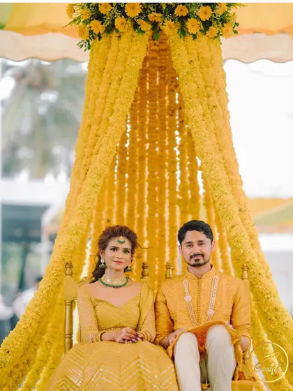 The couple seated under a stunning canopy of marigold strings for their Haldi ceremony.