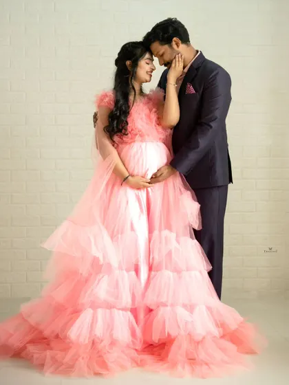 A tender moment between the couple during their studio maternity session. The contrast between the voluminous pink gown and the sharp suit creates a balanced and beautiful composition.