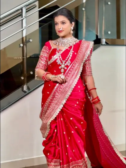 The final look of the red bridal saree, perfectly pleated and secured. The bride looks confident and ready for her grand entrance.
