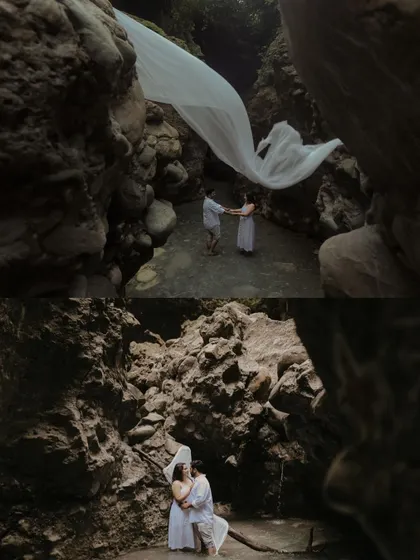 A dramatic pre-wedding shot using a long, flowing white fabric to add movement and artistry to the couple's portrait within a stunning natural cave.