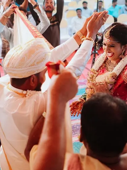 A candid moment of pure joy as the bride and groom participate in the wedding rituals, surrounded by their loved ones. The happiness on their faces is truly contagious.