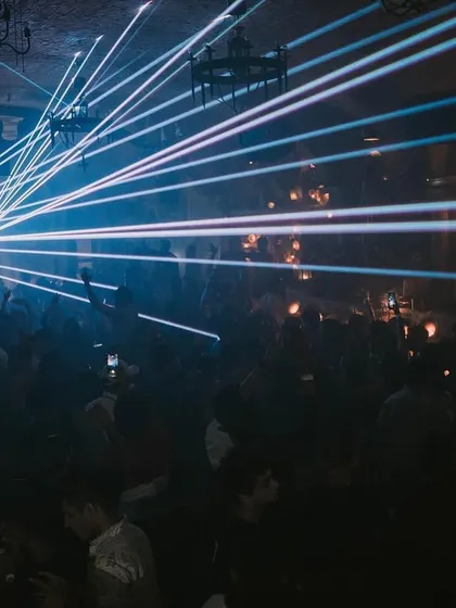 An intense laser show at a Halloween event, creating a web of light over the entire venue.